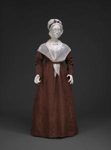 A lappet cap displayed with a red empire dress and white neckcloth.