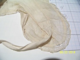 Close up of lappet end, showing lace edging and tape to tie the ends. 