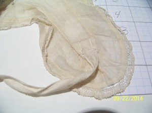 Close up of lappet end, showing lace edging and tape to tie the ends. 