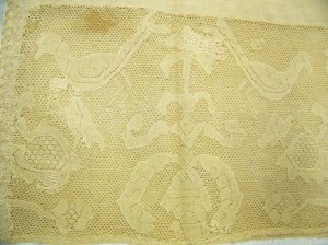 Cap McCord Museum #M980.4.26 photo by author. Close up of lace, with motif of birds and flowers. 