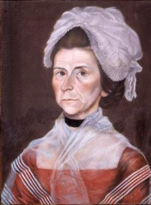 Woman in red gown and large loose cap.